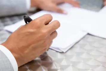 mão assinando papéis relacionados ao processo de abertura de empresas